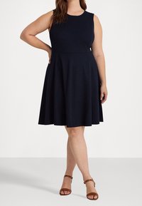 Bezramenné námořnické šaty s přiléhavým korpusem a rozšířenou sukní. Vyrobeny z hladké tkaniny, mají kulatý výstřih a žádné viditelné vzory.