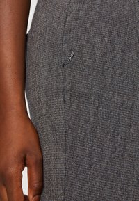 Grå textilerad tyg med ett subtilt mönster, med en sidoficka och en liten märkt etikett som läser "ONLY" i närheten av s ömmen.