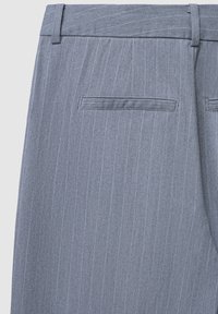 Pantaloni grigi a righe sottili con una consistenza liscia, dotati di vita, passanti per cintura e una singola tasca posteriore.