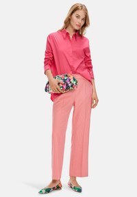 Pink long-sleeve button-up shirt, light pink striped wide-leg pants, and floral-patterned clutch. Green and floral flats complete the outfit.