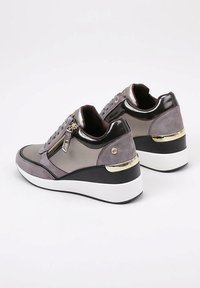 Zapatillas cuña en ante gris con acentos metálicos, que presentan una cremallera lateral, puntera redonda y una suela de plataforma blanca con detalle en dorado.