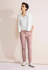 Bílá texturovaná bunda s kulatým límcem, spárovaná s bílým tílkem a růžovými přiléhavými kalhotami. Doplněno bílými teniskami.