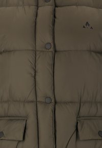 Olivengrüne Pufferjacke mit gestepptem Design, schwarzen Druckknöpfen und zwei Fronttaschen. Weicher Stoff mit sichtbaren Nähten.