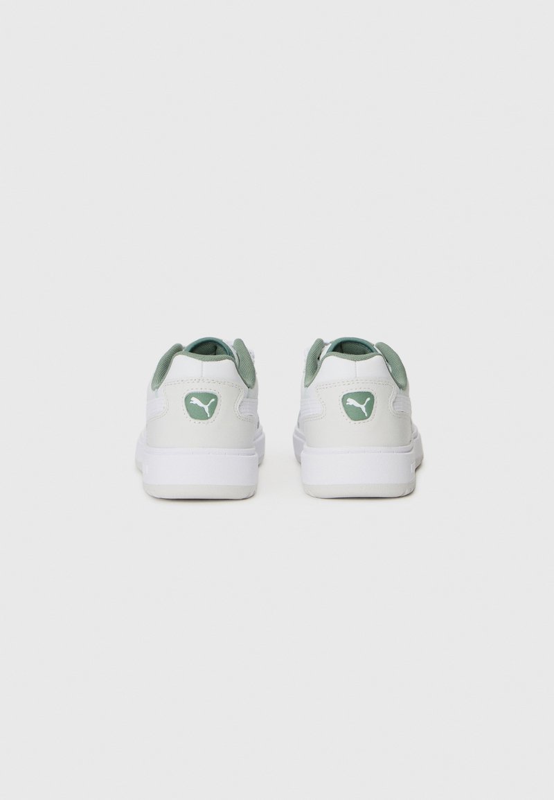 Sneaker bianca con accenti verdi. Materiale in pelle liscia, forma arrotondata, collo imbottito e dettaglio del logo sul tallone. Design minimalista.