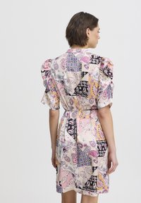 Rochie cu mânecă scurtă în culori pastelate, cu motive paisley și geometrice. Prezintă mâneci bufante și o talie strânsă, fiind confecționată dintr-un material neted.