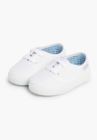 Scarpe da ginnastica bianche con profilo basso, dotate di suola in gomma testurizzata e fodera a scacchi blu. Inclusi lacci e dettagli di cucitura.