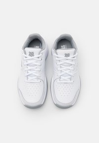 Valkoiset urheilukengät harmailla yksityiskohdilla, joissa on sileä nahka- ja verkkomateriaali, pyöreä kärki, rei'itys hengittävyyden parantamiseksi ja nauhakiinnitys.