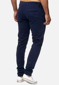 Navyblå chinos i bomull med slim fit. Har två bakfickor, subtila sömmar och sneakers med vit sula.