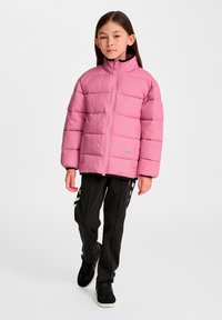 Ljusrosa vadderad jacka med hög krage och horisontell quiltad design, kombinerad med svarta mjukisbyxor med vita ränder.