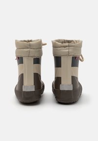 Bottes de pluie marron et beige avec une finition brillante, dotées d'un revers plié, d'un cordon de serrage et d'accents rayés sur le côté. Semelle texturée.