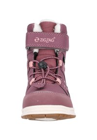 Botte imperméable violette avec un intérieur en peluche, des lacets élastiques, une sangle ajustable et une semelle extérieure en caoutchouc. Présente un logo zigzag sur le dessus.