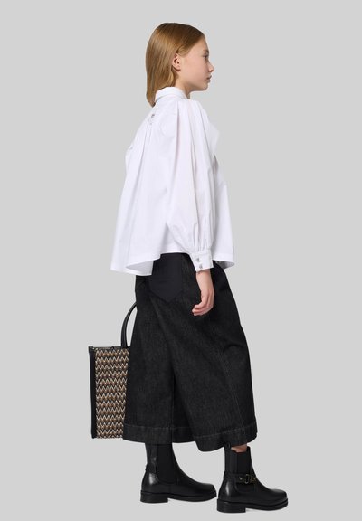 White puff-sleeve shirt, high neck, paired with wide-leg dark jeans and black ankle boots. Black and woven bag accent at the side.