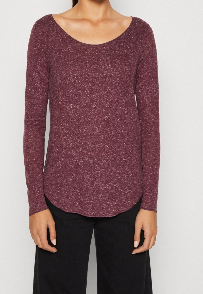 Camicia bordeaux a maniche lunghe con scollatura a girocollo, realizzata in tessuto testurizzato, con orlo curvo e vestibilità slim. Abbinata a pantaloni neri.