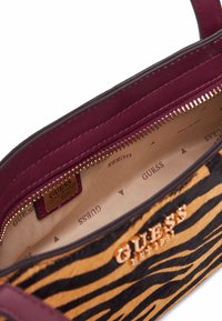 Borsa a strisce zebrate nera e arancione con interno bordeaux. Presenta minuteria color oro, chiusura con zip e marchio interno.