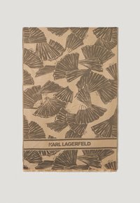 Brun tørklæde med et mønster af sorte ginkgo-blade, tekstureret overflade og frynser langs kanterne. "KARL LAGERFELD" logoet trykt i bunden.