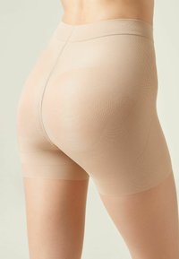 Beiga formande shorts gjorda av ett mjukt, elastiskt material med sömlös design, som har en konturerande effekt vid höfter och lår.