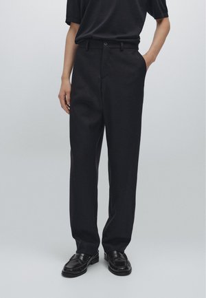 Dark tailored trousers with a straight-leg design. Made of textured fabric, featuring a front button closure and side pockets.