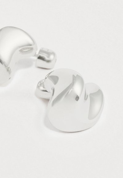 Brincos prateados curvos com superfície lisa e brilhante e formas arredondadas, apresentados com um fecho de encaixe seguro para uso.