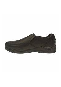 Zapatos negros sin cordones, hechos de un material sintético suave, con un perfil bajo y una punta redondeada; cuentan con paneles laterales elásticos para facilitar su uso.