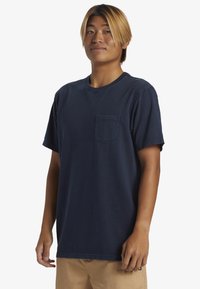 Mörkblå bomullströja med korta ärmar, rund halsringning och en enda bröstficka. Har avslappnad passform och minimala sömdekorationer.