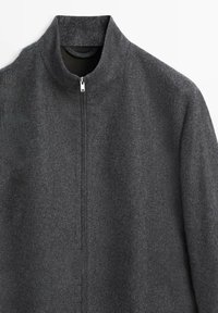 Graue Reißverschlussjacke aus strukturiertem Stoff. Hoher Kragen, minimalistisches Design und ein einzelner Reißverschluss vorne. Keine sichtbaren Taschen.