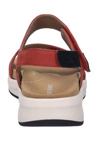 Czerwone sandały z tylnym paskiem i regulowanym zapięciem. Posiadają wyściełaną wkładkę, białą podeszwę środkową i czarną gumową podeszwę zewnętrzną zapewniającą przyczepność.