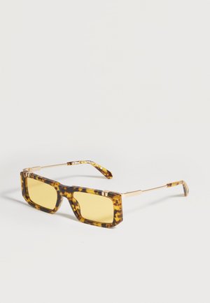 Lunettes de soleil rectangulaires en écaille de tortue avec verres teintés jaunes et branches fines en métal doré sur fond blanc.