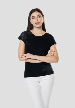 Top nero a maniche corte con un motivo testurizzato a foglia di palma sul lato sinistro. Abbinalo a pantaloni bianchi aderenti per un contrasto. Tessuto liscio, scollo arrotondato.