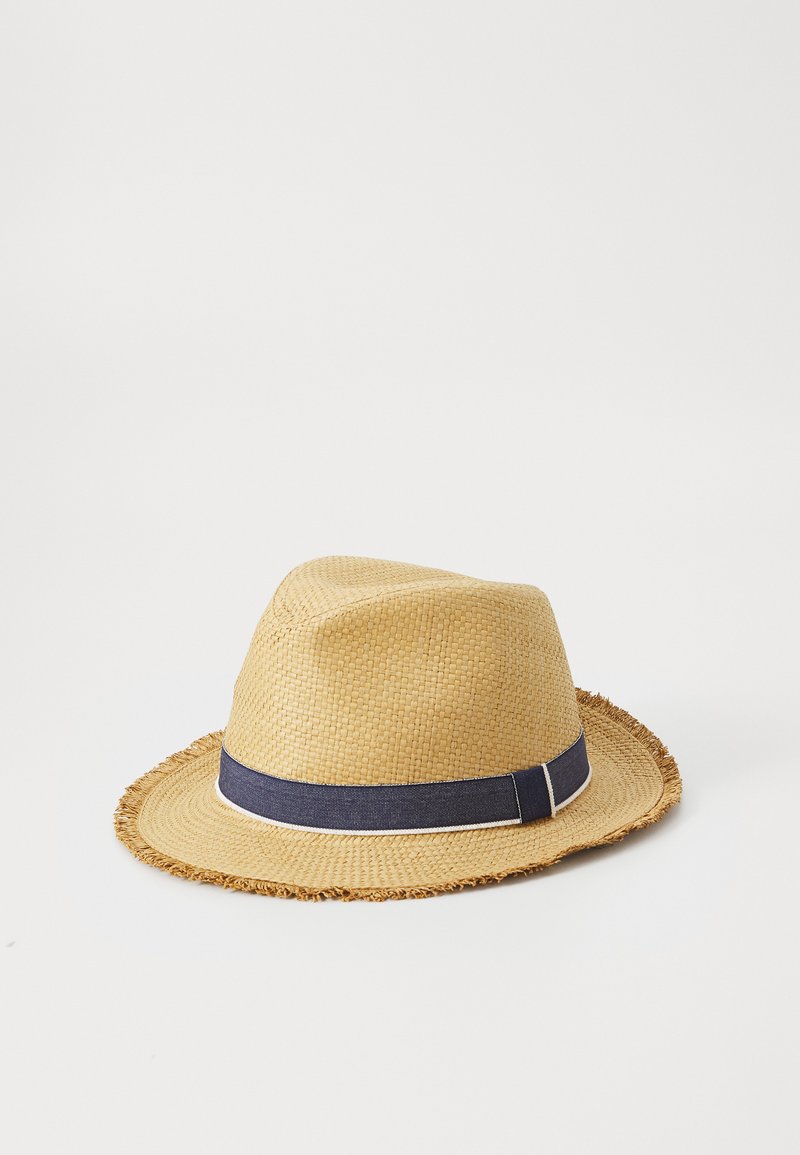 Sombrero de paja tipo fedora con un ala ancha y deshilachada, que presenta una banda azul marino con una franja blanca. El material es tejido, lo que proporciona una apariencia texturizada.