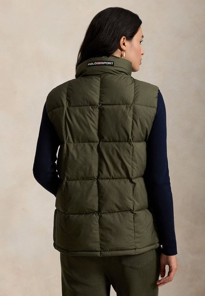 Πράσινο γιλέκο με καπιτονέ ύφασμα και ψηλό γιακά, με μεγάλα γεμισμένα τμήματα. Το πίσω μέρος φέρει λογότυπο Polo Sport στο ύψος του λαιμού.