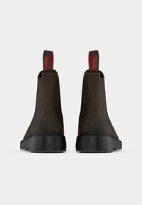 Rjavi usnjeni gležnjarji imajo gladko teksturo, okroglo obliko, črn gumijast podplat, rdeč jeziček za poteg in stranski elastični del za enostavno obuvanje.