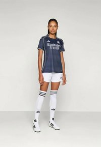 Mornarsko plava atletska majica s bijelim detaljima, s logotipom "Emirates Fly Better", u kombinaciji s bijelim šortsem i čarapama do koljena s crnim prugama.