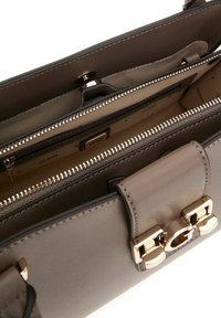 Sac à main en cuir gris avec une texture lisse, quincaillerie en ton doré, plusieurs compartiments et fermeture à pression magnétique. Intérieur doublé.