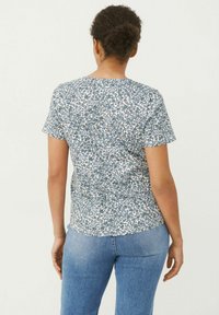 Kurzärmliges Oberteil mit einem blauen Blumenmuster auf weißem Hintergrund, aus leichtem Material gefertigt, mit Rundhalsausschnitt und lockerer Passform.
