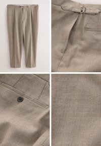 Beige szövetnadrág, pleats-szel, gombos záródással és övhurkokkal. Az anyagnak finom textúrája van, és hátsó zsebdísszel rendelkezik.