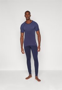 Marineblå treningssett med en tettsittende T-skjorte med teksturert mønster og matchende lange leggings, begge laget av elastisk stoff.