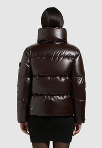 Brown glossy puffer jacket with a high collar and horizontal seams, featuring a side logo patch and a fitted silhouette. Textured fabric.