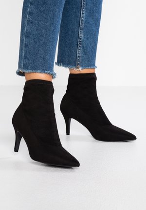 Czarne botki za kostkę wykonane z zamszu, z ostrym noskiem i smukłym obcasem typu szpilka. Gładka faktura z dopasowanym krojem, bez widocznych elementów metalowych.