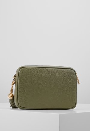 Prostokątna, oliwkowozielona skórzana torba na ramię z złotym zamkiem i frędzlem z łańcuszka, prezentowana na białej powierzchni na tle szarego tła.