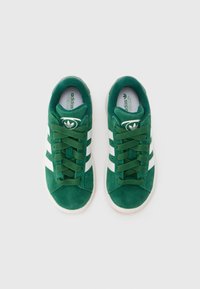 Grønn nubuk sneakers med hvite lærstriper, rund tå og flat snøring. Har en merket tunge og polstret krage.