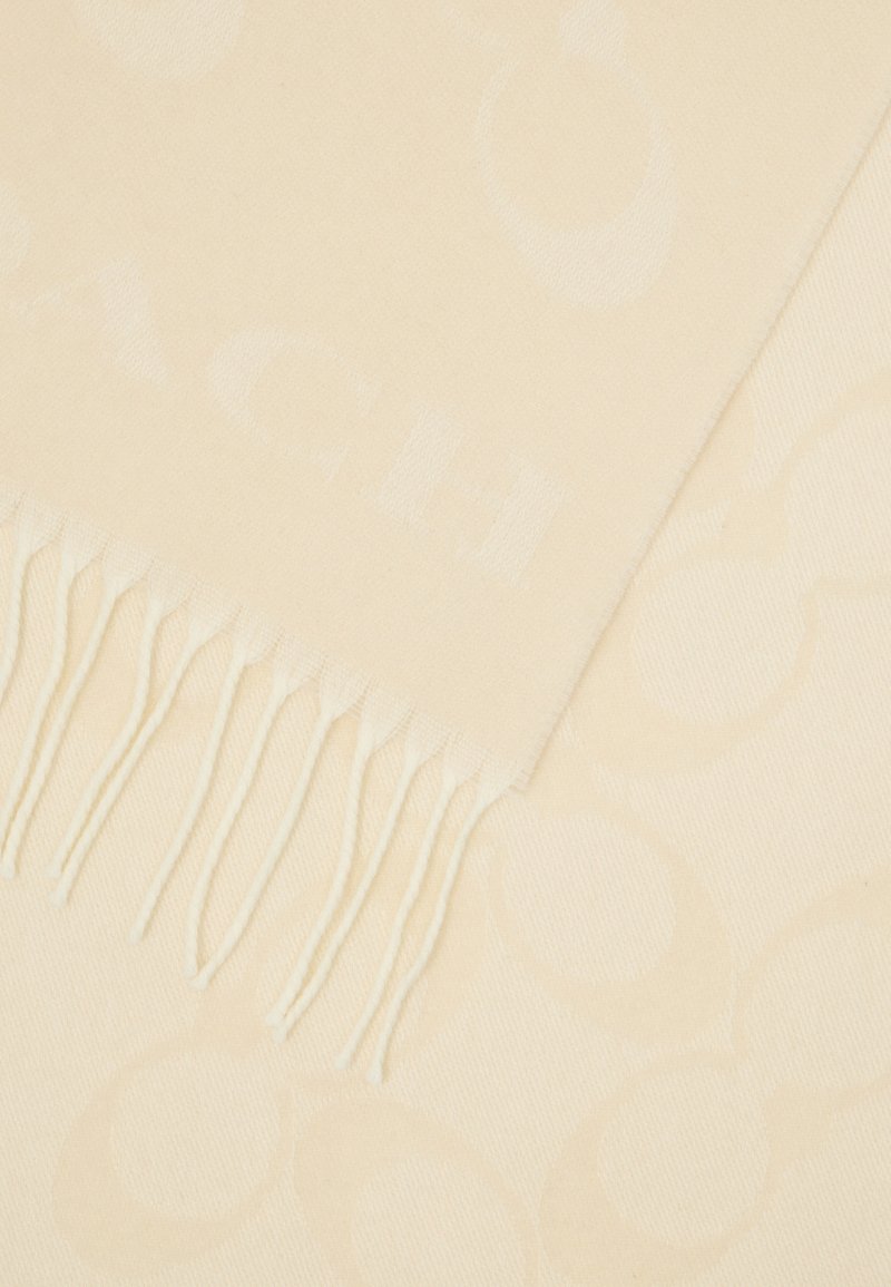 Cremfarbener Schal aus weichem Material, mit einem dezenten Logomuster, das an einer Kante mit zarten Fransen abgeschlossen ist.