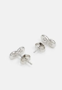 Orecchini a perno in metallo argento con un design liscio e arrotondato. Presentano una forma a doppio cerchio che riflette la luce.
