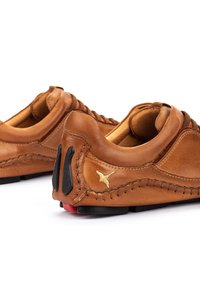 Brown leather shoes with a low profile, detailed stitching, black rubber accents, and a subtle logo on the heel.
