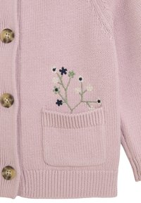 Jasnoróżowy dziergany kardigan z brązowymi guzikami, kieszonką z przodu i haftowanymi małymi kwiatkami w kolorze zielonym, białym i ciemnoniebieskim na kieszeni.
