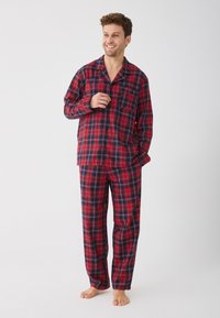 Piros és tengerészkék kockás pizsama, puha anyagból készült, gombos inggel, zsebbel és laza szabású nadrággal.