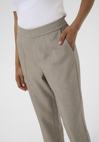 Pantalons taillés gris clair, en tissu texturé, avec des poches latérales, une taille lisse et des jambes droites.