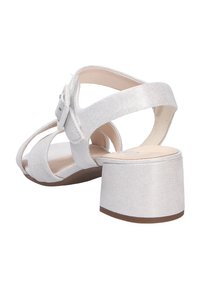 Sandales à talons blancs avec un tissu texturé, design à bout ouvert et bride de cheville réglable avec un accent en nœud. Talon bloc épais.
