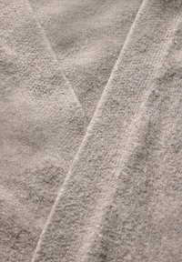 Tissu gris clair avec une texture douce, présentant un motif tissé subtil et un léger éclat. Drapé de manière diagonale.