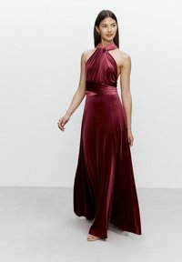 Burgunderfarbenes Samt-Halterkleid mit gefältelter Vorderseite, tailliertem Schnitt und fließendem Rock. Glatte Textur und minimalistisches Design ohne zusätzliche Muster.