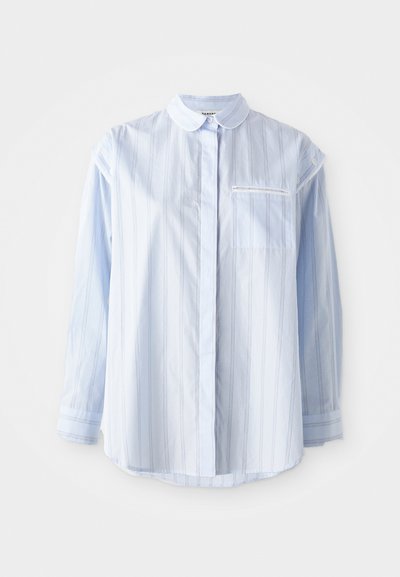 Jasnoniebieska koszula z długim rękawem w pionowe paski, z kołnierzykiem na guziki, pojedynczą kieszenią na klatce piersiowej oraz mankietami wykończonymi bandą. Wykonana z miękkiej bawełny.